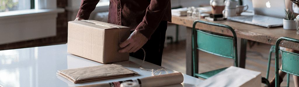man verpakt doos op bureau – internationaal verzenden