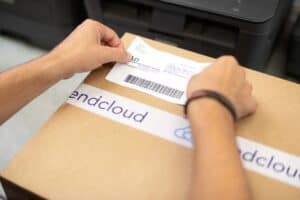 Versandetikett wird an einem mit Sendcloud-Klebeband versiegelten Paket angebracht