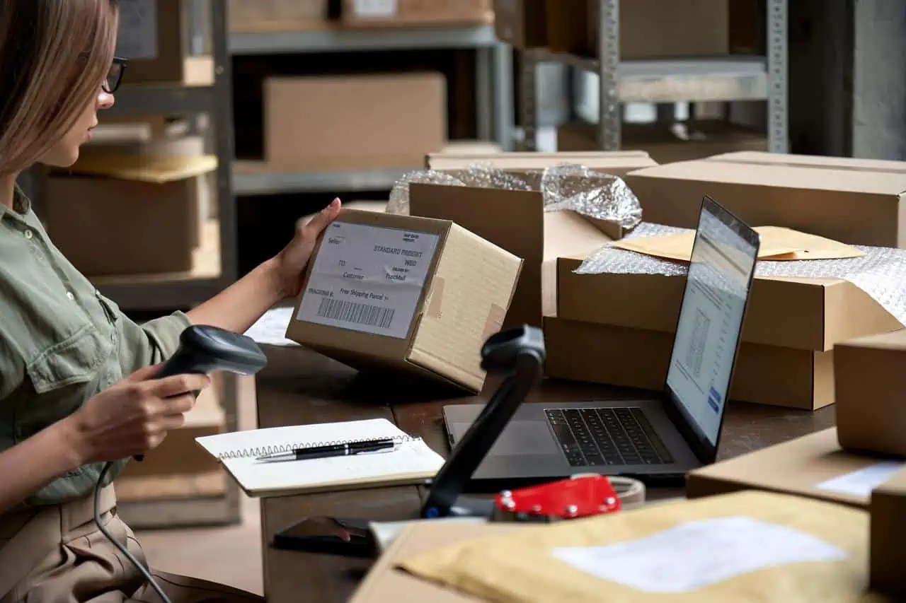 Operatore logistico che scansiona un pacco con un'etichetta di reso (RMA) e gestisce le operazioni di reso attraverso un computer.