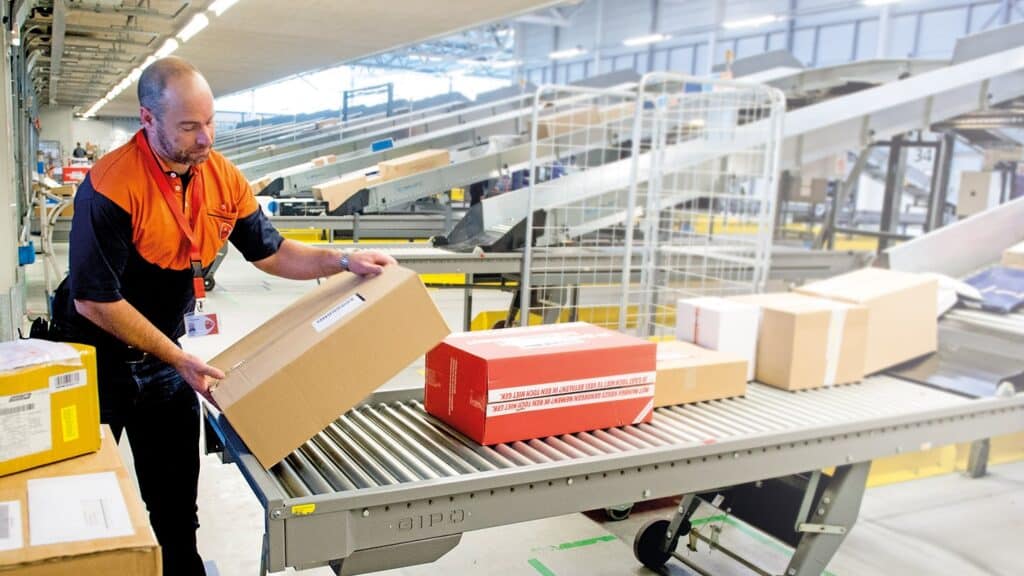 PostNL employee handling parcels on a conveyor belt