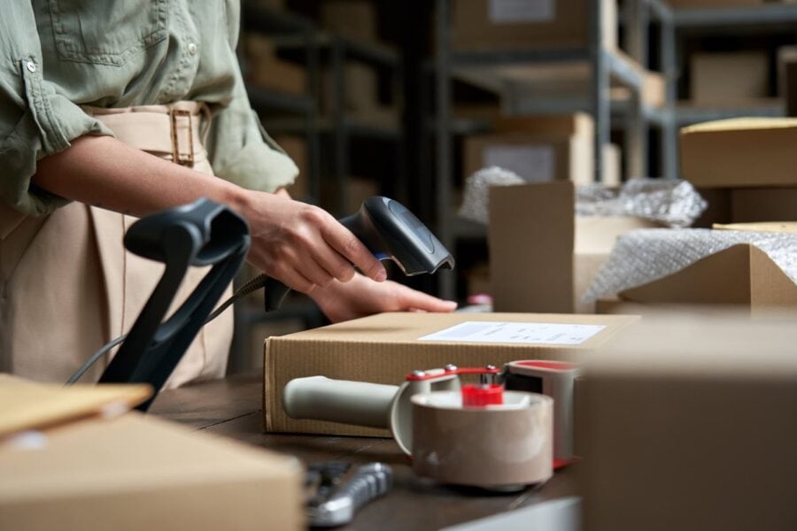 Female merchant in green shirt scanning a parcel in a warehouse